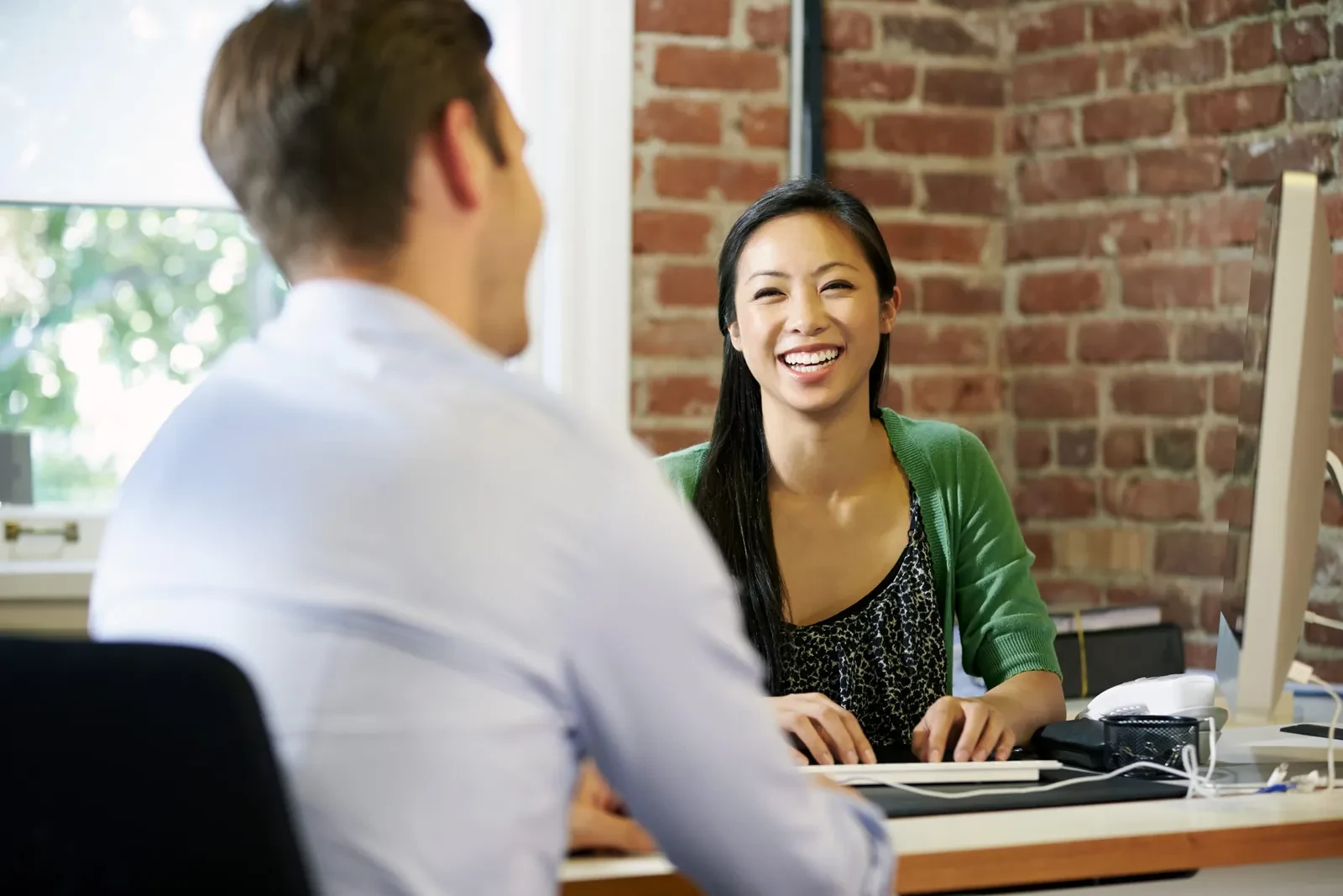 Happy woman smiling at person on other side of desk