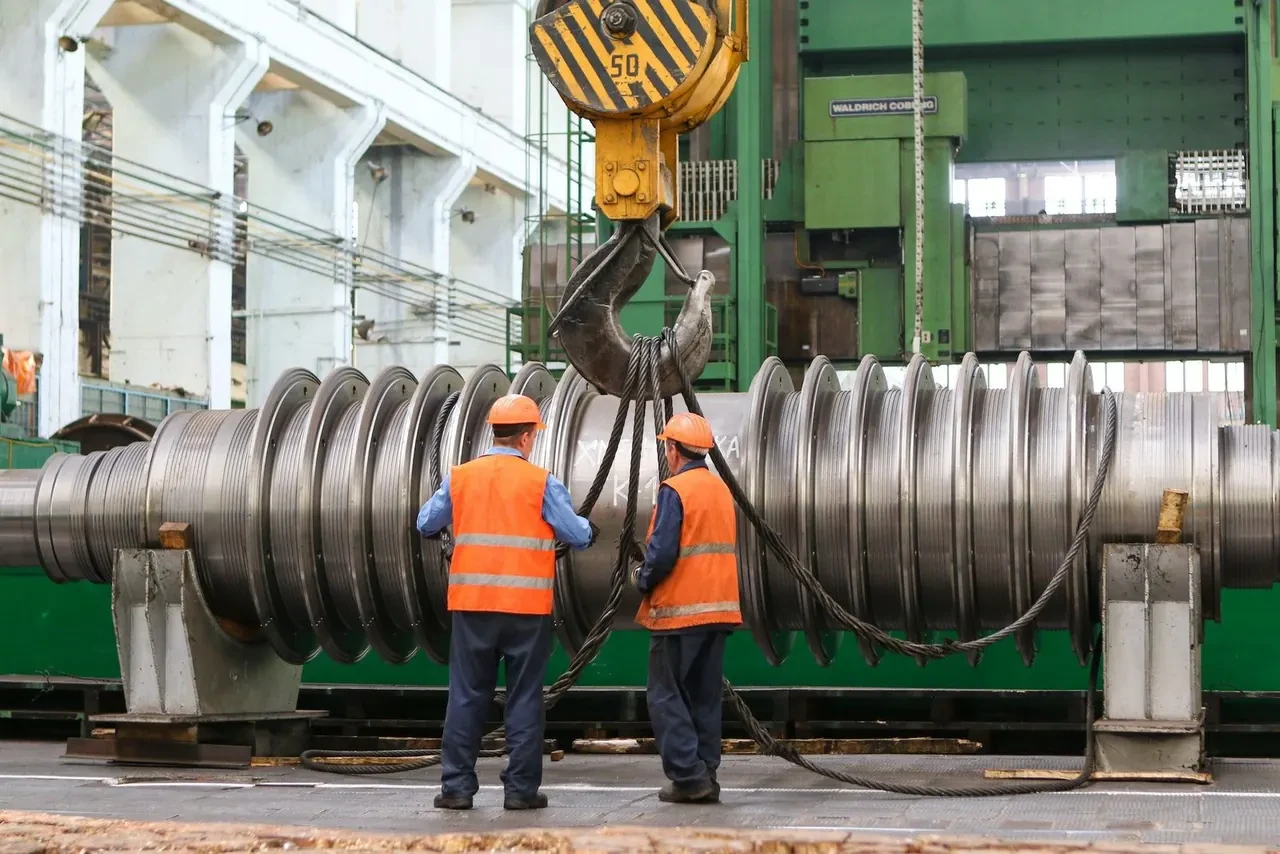 Two workers in safety vests on a factory floor