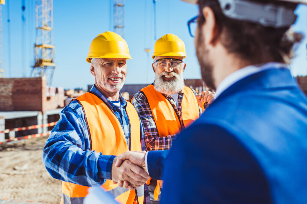 Two construction workers shaking hands with manager
