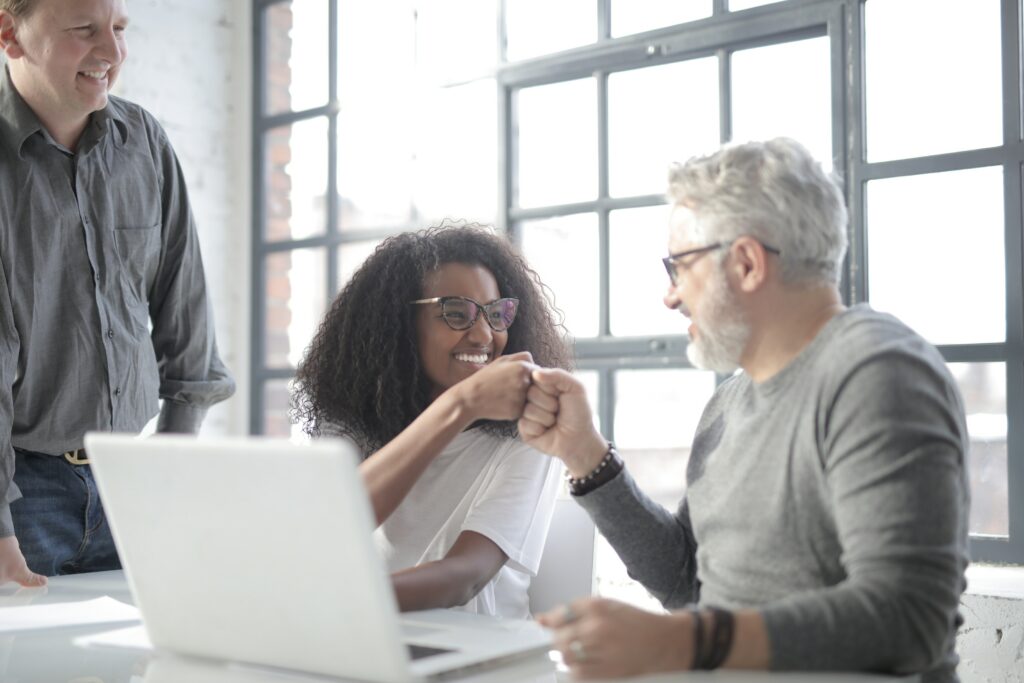 Happy Co-Workers bumping fists in-front of a laptop